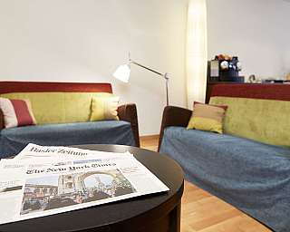 A living room with two sofas and newspapers on a table.