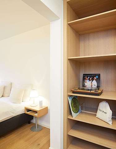 Gemütliches Schlafzimmer mit Bett, Nachttisch und Holzregal.