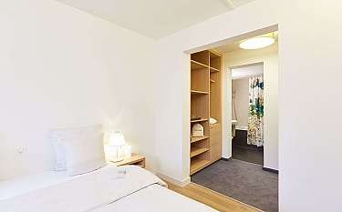 Ein helles Schlafzimmer mit einem angrenzenden Badezimmer und Holzregalen.