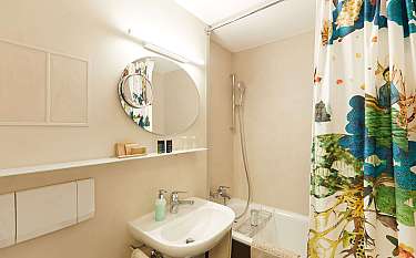 Kompaktes Badezimmer mit Waschbecken, Spiegel und Duschbereich.