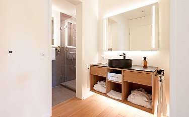 Kompaktes Badezimmer mit Waschbecken, Spiegel und Duschbereich.