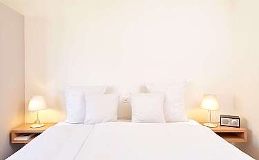 Gemütliches Schlafzimmer mit weißen Kissen und Nachttischlampen.