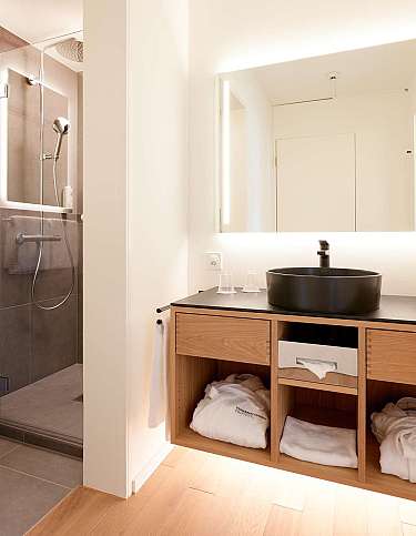 Elegantes Badezimmer mit Dusche, Waschbecken und Handtüchern.