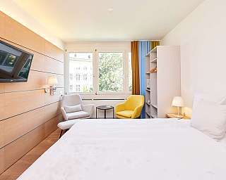 Ein modernes Hotelzimmer mit Doppelbett und Schreibtisch.