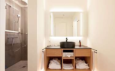 Helles Badezimmer mit Dusche, Waschbecken und Handtüchern.