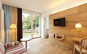 Modernes Hotelzimmer mit Sofa, Tisch und Fernseher.