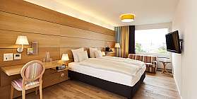 Helles Hotelzimmer mit Doppelbett, Schreibtisch und Fenster.