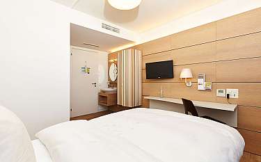 Ein modernes Hotelzimmer mit einem Bett, TV und Waschbecken.