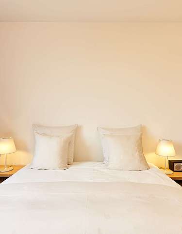 A bedroom with two pillows, bedside tables, and curtains.