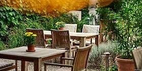 Holztische und Stühle in einem grünen Garten mit Pflanzen.