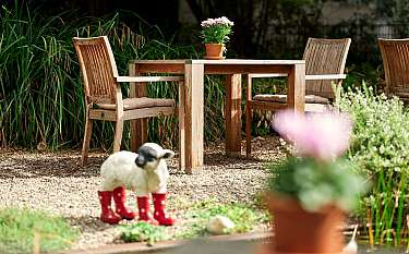 Holztisch mit Stühlen und einer Pflanze im Garten.