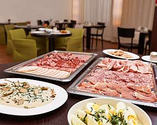 Ein Buffet mit verschiedenen Wurstsorten und einem Salatgericht.