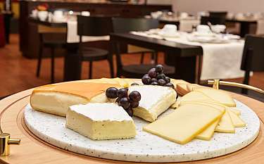 Verschiedene Käsesorten auf einer Marmorplatte mit Trauben.