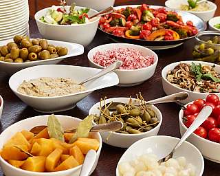 Bunte Auswahl an Salaten, Dips und Gemüse in Schalen.