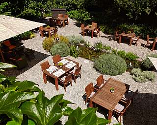 Ein einladender Garten mit Holztischen und Pflanzen.