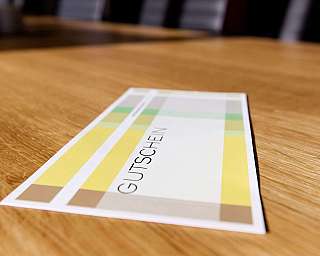 A voucher with a colourful design on a wooden table.