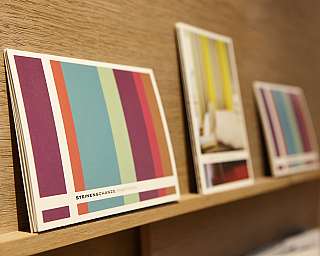 Colourful sample cards on a wooden shelf.